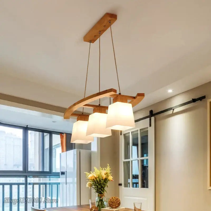 A modern wood bird glass pendant light with three off-white fabric shades and a natural-toned curved wooden frame
