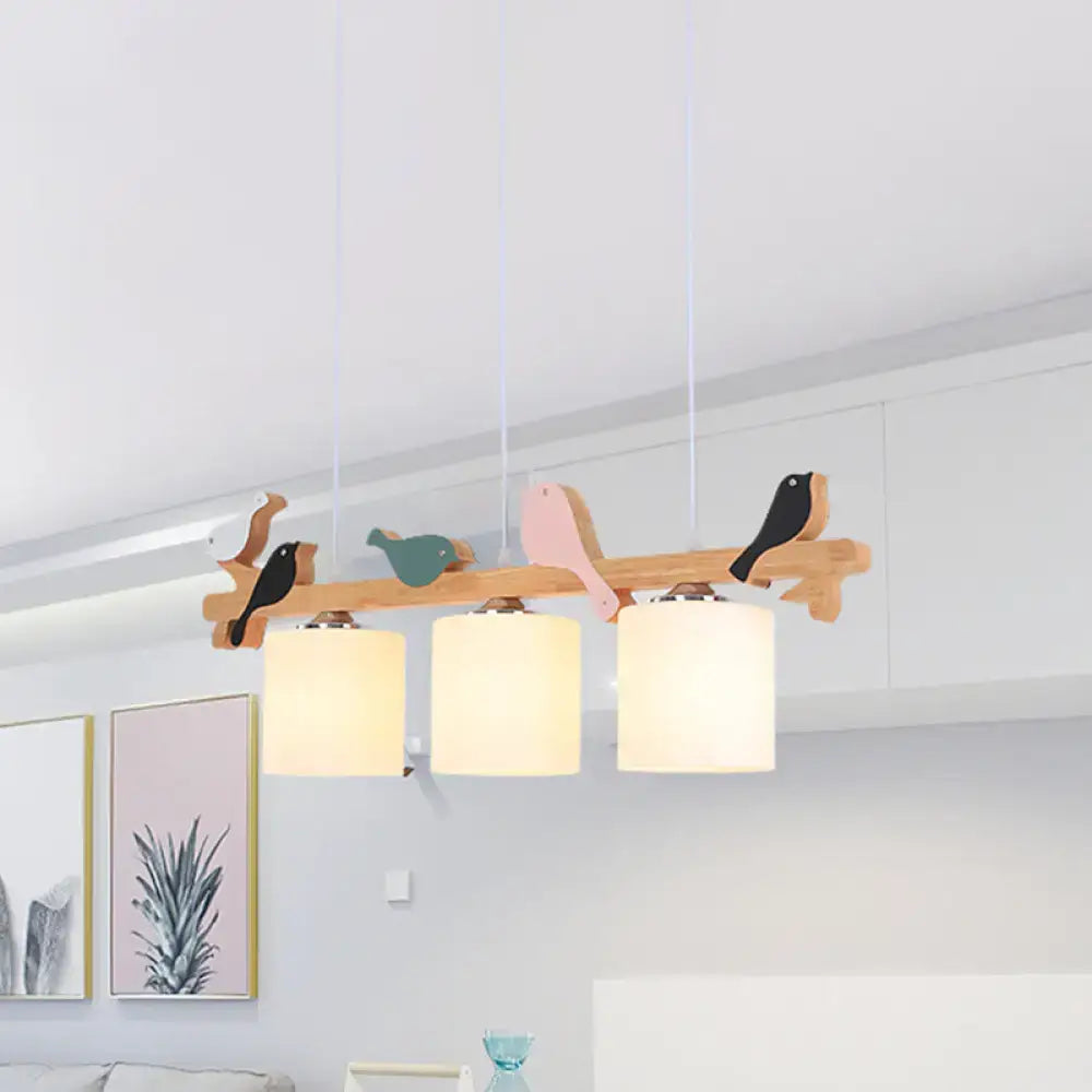Wooden branch-style pendant light with three frosted glass cylindrical shades and colorful bird cutouts for barrel island decor