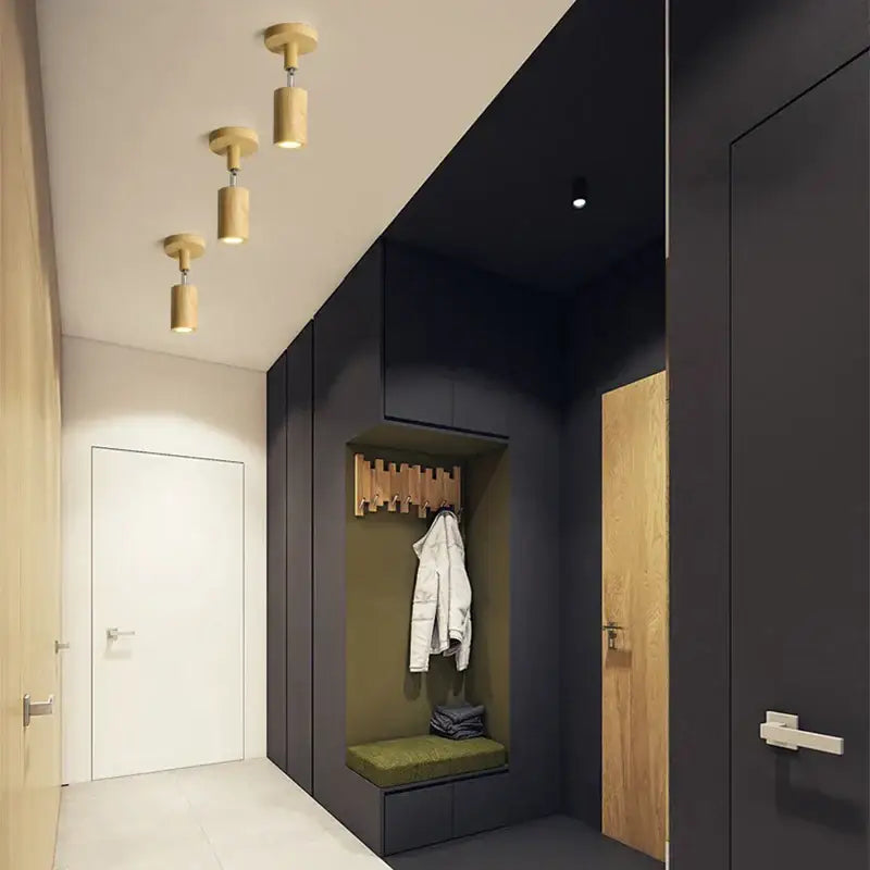 Modern wood ceiling light with two beige spotlight heads in a minimalist hallway featuring black cabinetry and wooden accents