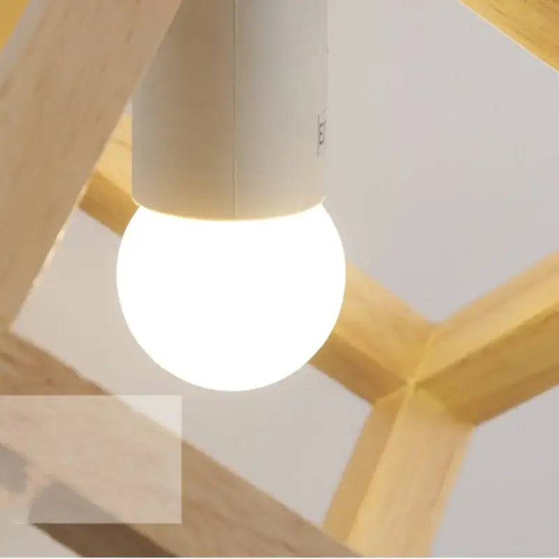 A glowing white led bulb with an off-white cylindrical base suspended in a light wood cube led wall light sconce