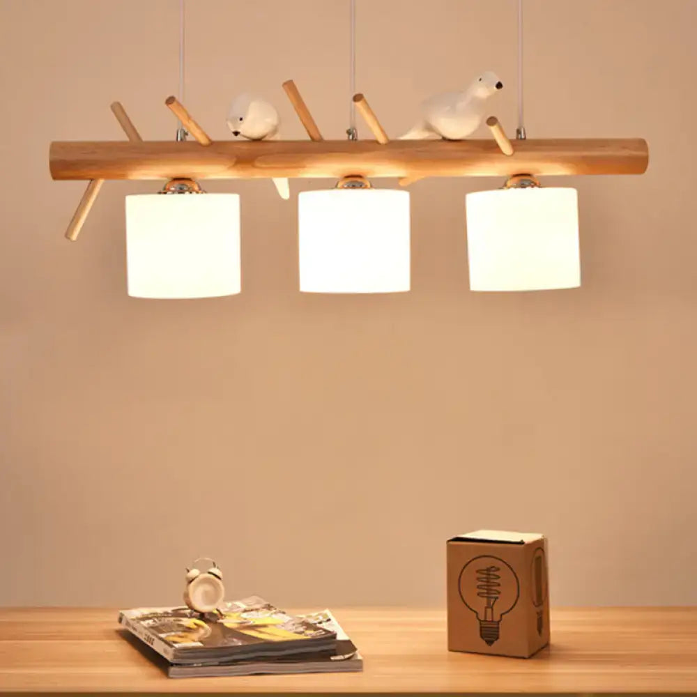 Modern wood cylinder hanging light with three white glass shades and decorative bird figurines for kitchen use