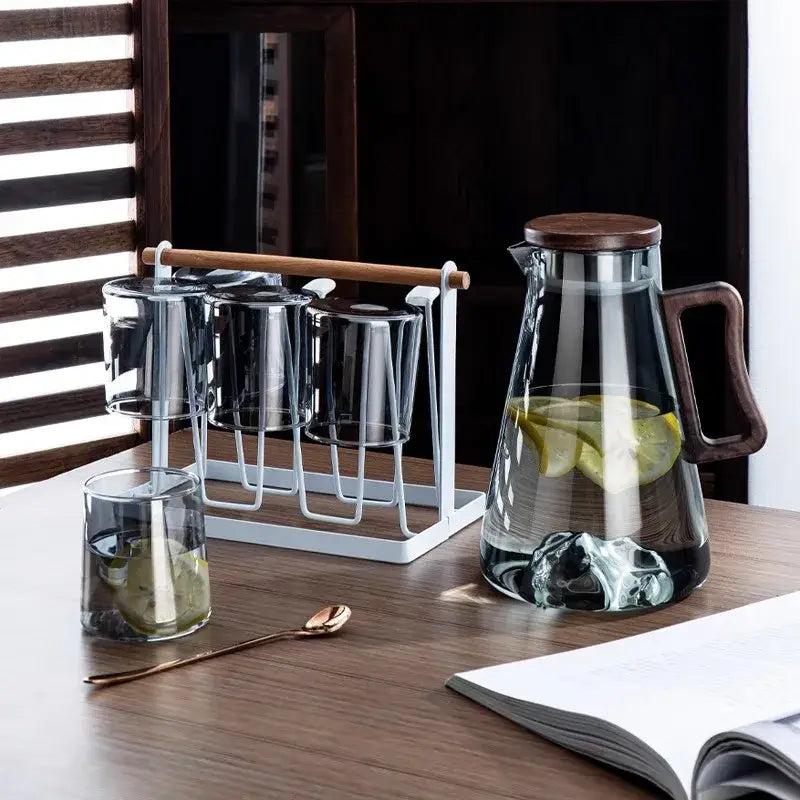 Clear glass cold water jug with modern dark wood handle and lid filled with water and lemon slices