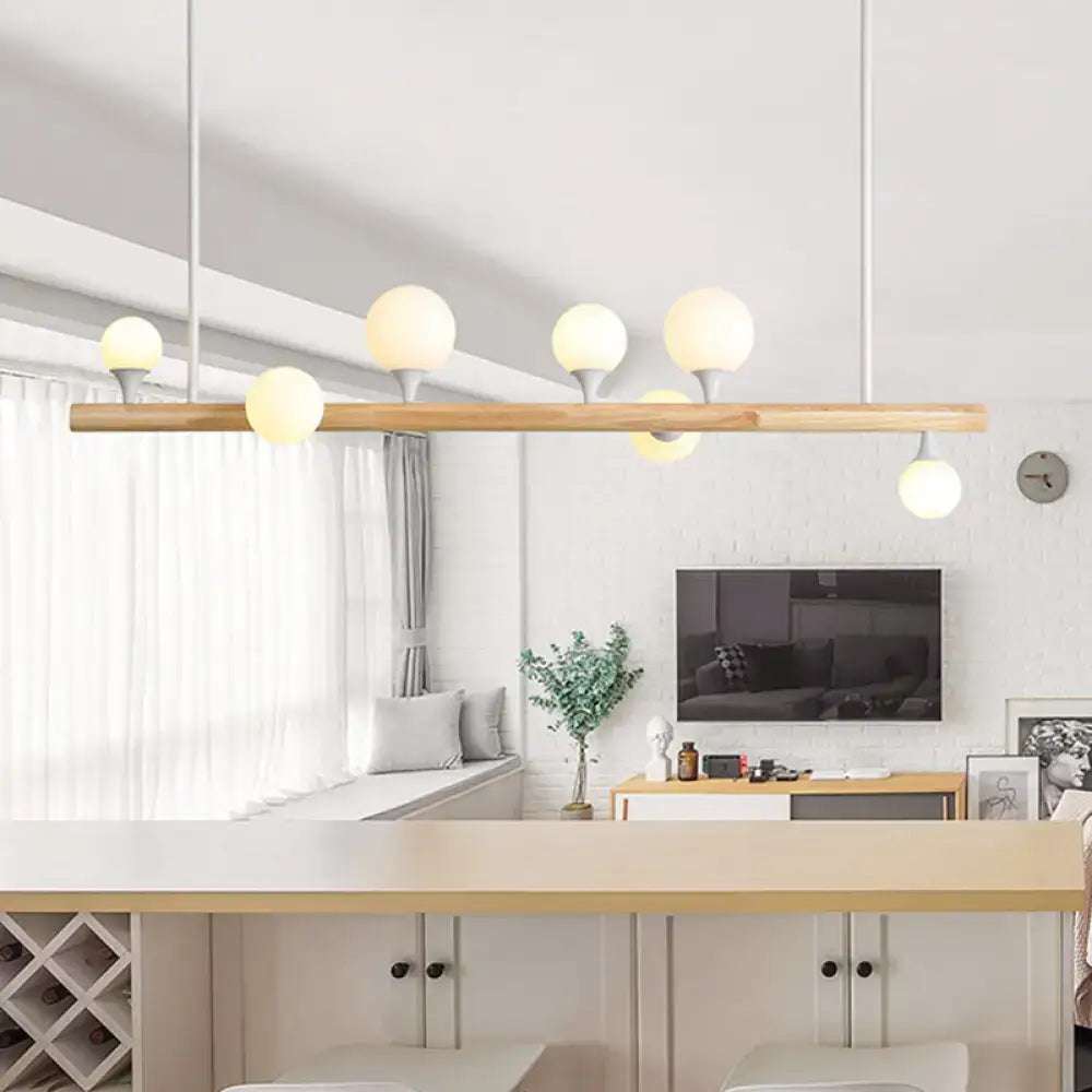 Modern wood island lamp with five frosted glass globe bulbs on a slender wooden bar for dining room use