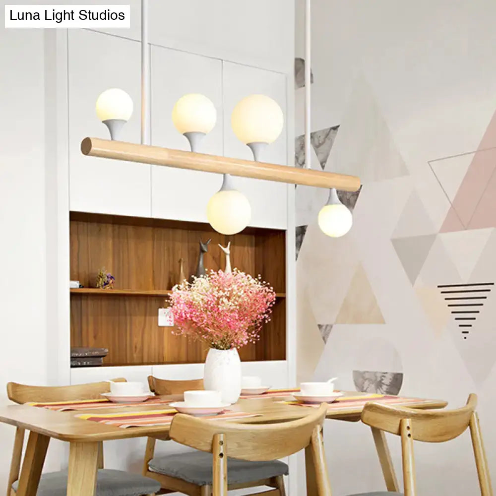 Modern wooden island lamp with four warm-glowing globe lights and natural bulb base for dining room use