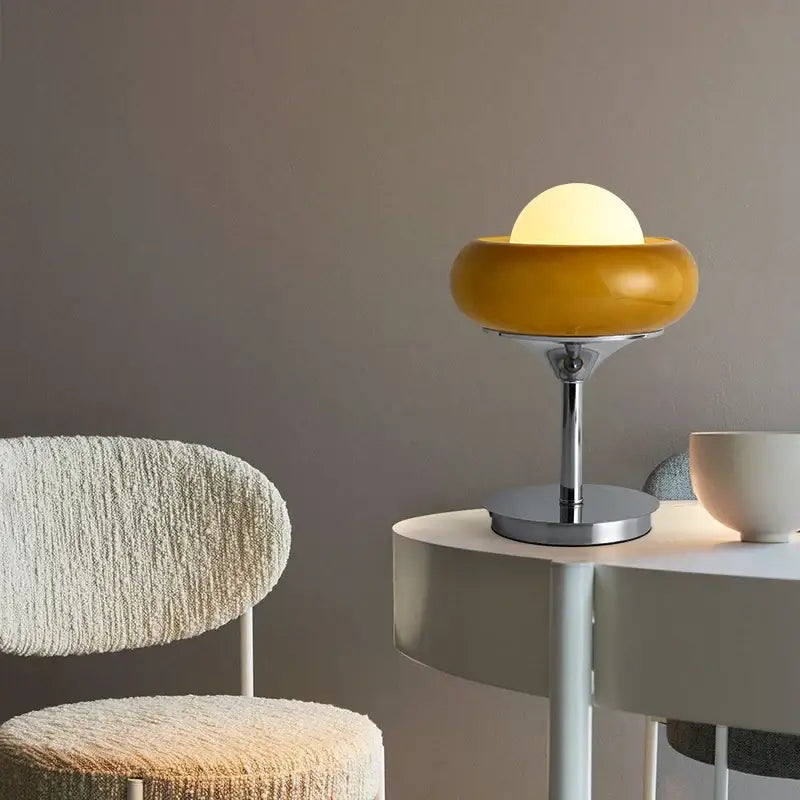 A modern yellow and chrome glass egg tart desk lamp with a glossy mustard-yellow dome for bedroom use
