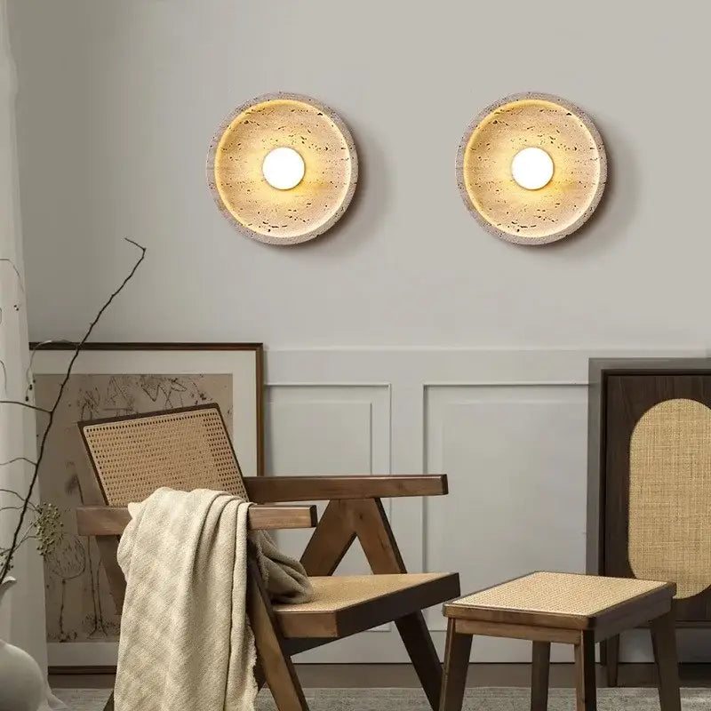 Two circular wall lamps with textured beige stone finish and warm led wall lamp centers for bedroom lighting