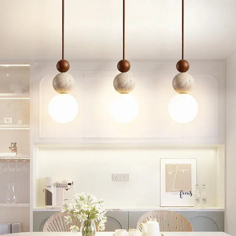 Three modern pendant lights with matte brown tops and textured concrete spheres featuring led bulb cord pendants