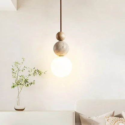 Minimalist pendant light with smooth wood and textured concrete spheres and led bulb hanging from brown cord pendant