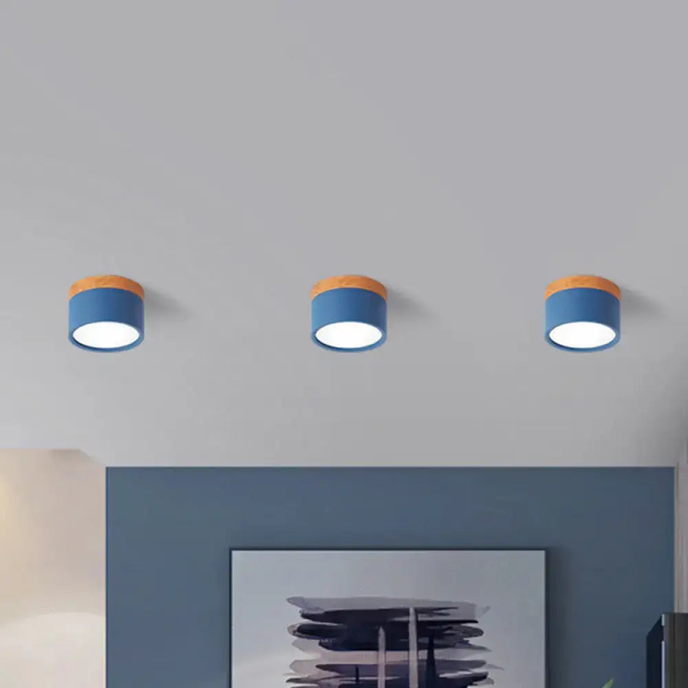 Three decorbites flush mount ceiling lights with blue metal shades and wooden tops emitting soft white glow for kitchen bar