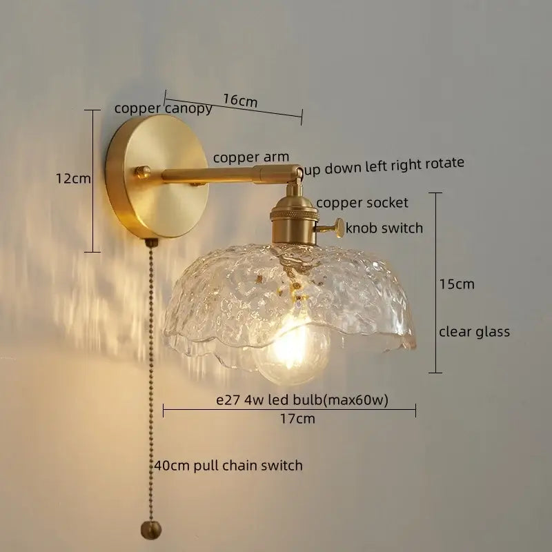Vintage-style wall lamp with brass-finished copper arm and ornate clear glass shade next to modern green glass LED wall light