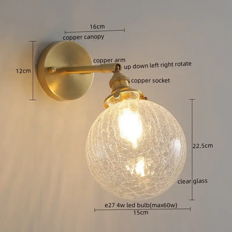 A vintage-style wall lamp with brass-finished copper arm and glowing crackled clear globe for bedroom light