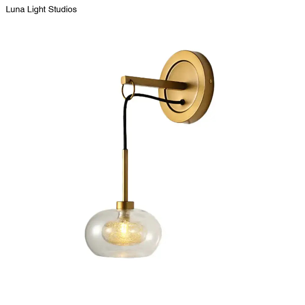 Gold-toned modernist wall sconce with amber white glass globe and black cord for bedroom drop lamp lighting