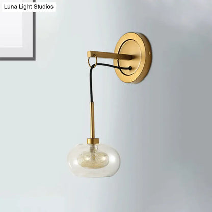 Gold-toned modernist bedroom wall sconce with amber white glass globe and black cord drop lamp