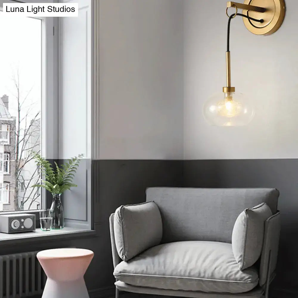 Gold-toned modernist wall sconce with amber white glass globe shade and black cord for bedroom lighting satisfaction guarantee