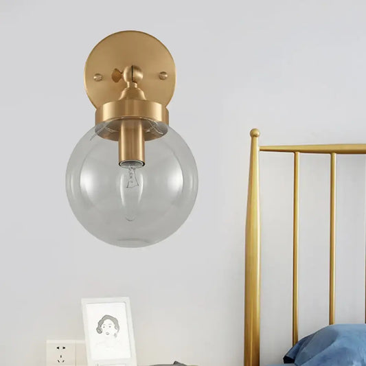 Gold-finished modernist ball wall lamp with clear glass globe and exposed bulb wall mounted for bedroom use