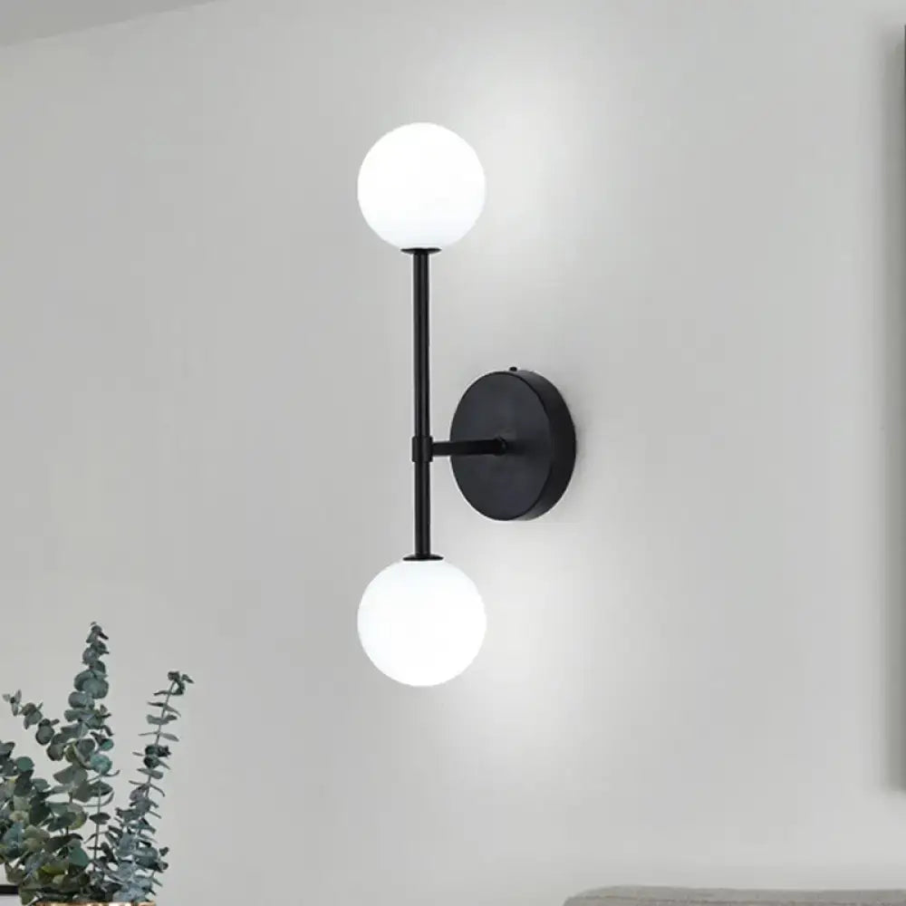 Modernist black wall sconce with gold finish and two frosted glass globe shades for living room lighting