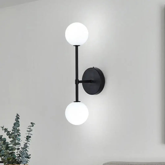 Modernist black wall sconce with gold finish and two frosted glass globe shades for living room lighting
