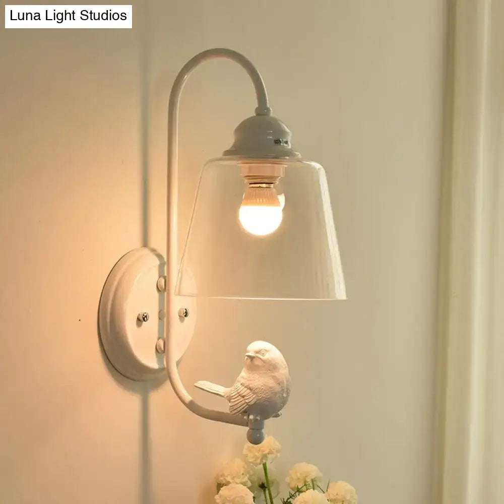 A delicate white ceramic bird on a black metal arm of a modernist black and white cone wall lamp with glass shade