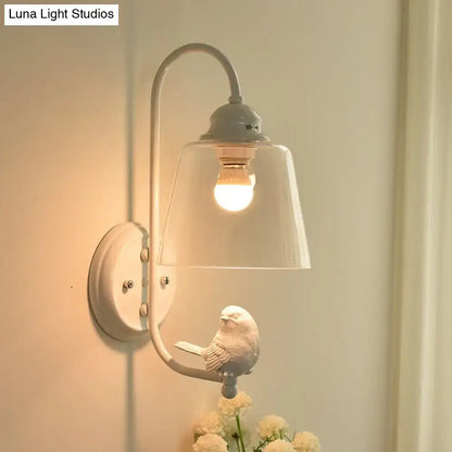 A delicate white ceramic bird on a black metal arm of a modernist black and white cone wall lamp with glass shade