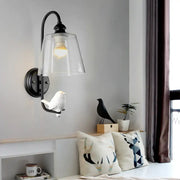 Modernist black metal cone wall lamp with clear glass shade and attached white bird figurine for bedroom use