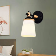 Modernist wall lamp with black and wood finish and cream glass shade ideal for bedroom lighting