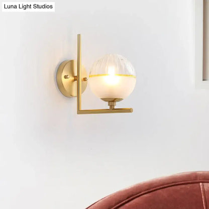 Modernist direct wired electric brass light fixture with frosted glass spherical globe and warm yellow accent band wall sconce