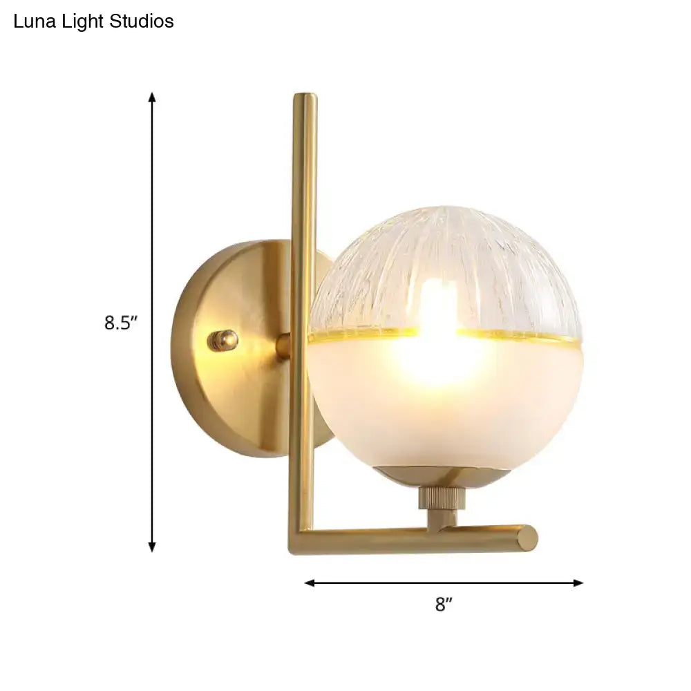 Modernist brass wall sconce with textured frosted glass globe and gold-trimmed base direct wired electric light fixture