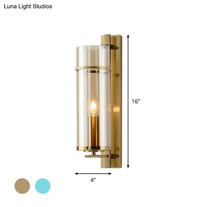 Modernist brass wall lamp with a clear cylindrical glass shade and exposed filament bulb for bedroom sconce light use