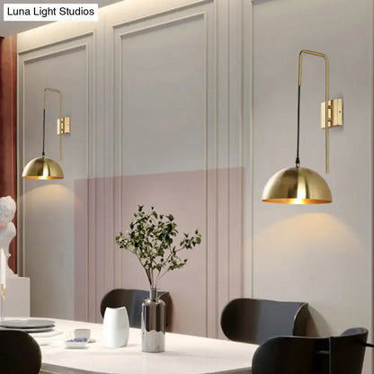 Modernist brass dome sconce wall light featuring curved arm and black cord as a bedroom light fixture