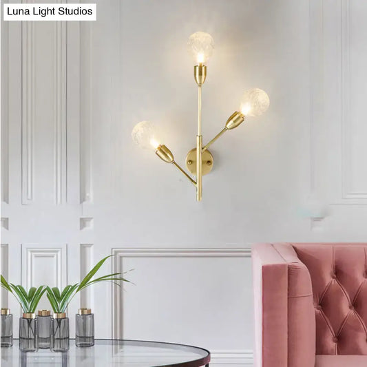 Modernist gold-toned wall mount light fixture with prismatic glass and three frosted bulbs for bedroom use