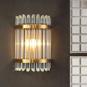 Modernist clear crystal wall sconce with gold finish and vertical glass tubes for elegant living room lighting