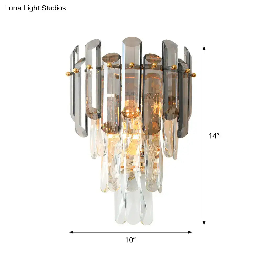 Modernist wall sconce with tiered clear and smoke gray glass panels accented by gold-toned hardware for bedroom use