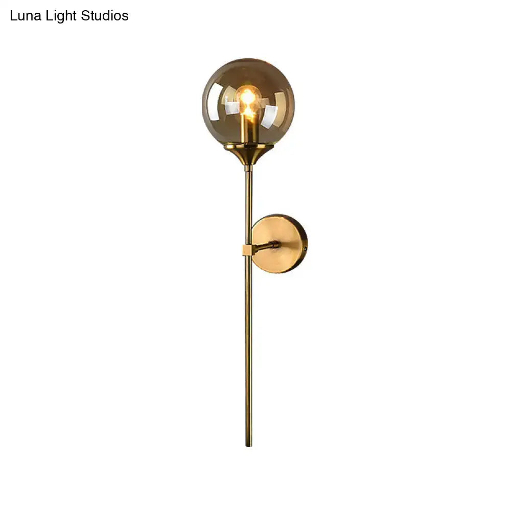Modernist gold glass round sconce lamp with brass finish and amber globe featuring exposed filament bulb for living room
