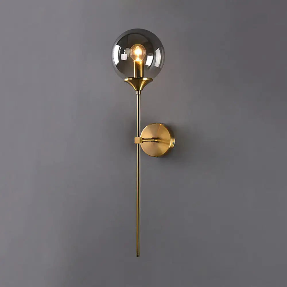 A sleek modernist gold glass round sconce lamp with brass and smoked glass globe for living room lighting
