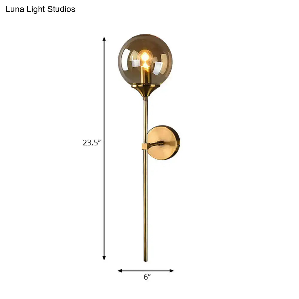 Modernist gold-toned round sconce lamp with smoked glass globe and slender metal stem for living room lighting