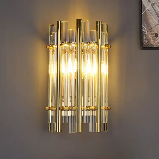 Modernist gold tubular wall sconce with clear glass tubes and brass accents for bedroom lighting