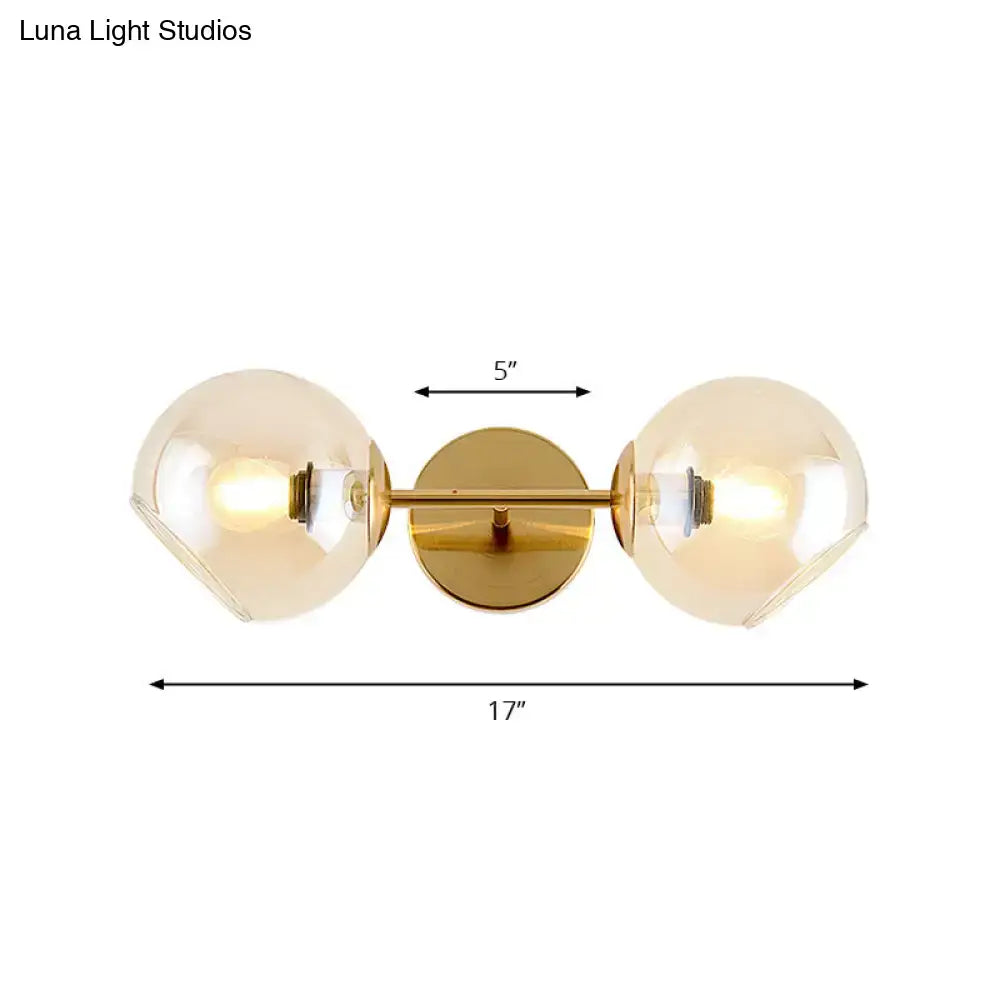 Modernist gold wall lamp with two amber glass shade globes and central circular mounting plate for living room