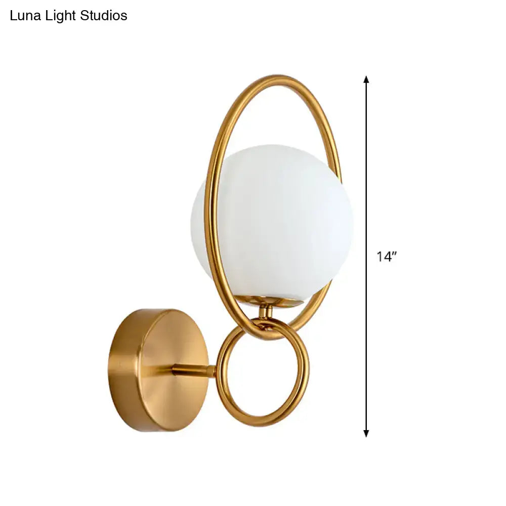 Modernist gold wall sconce with interlocking rings and frosted white glass shade for bedroom lighting