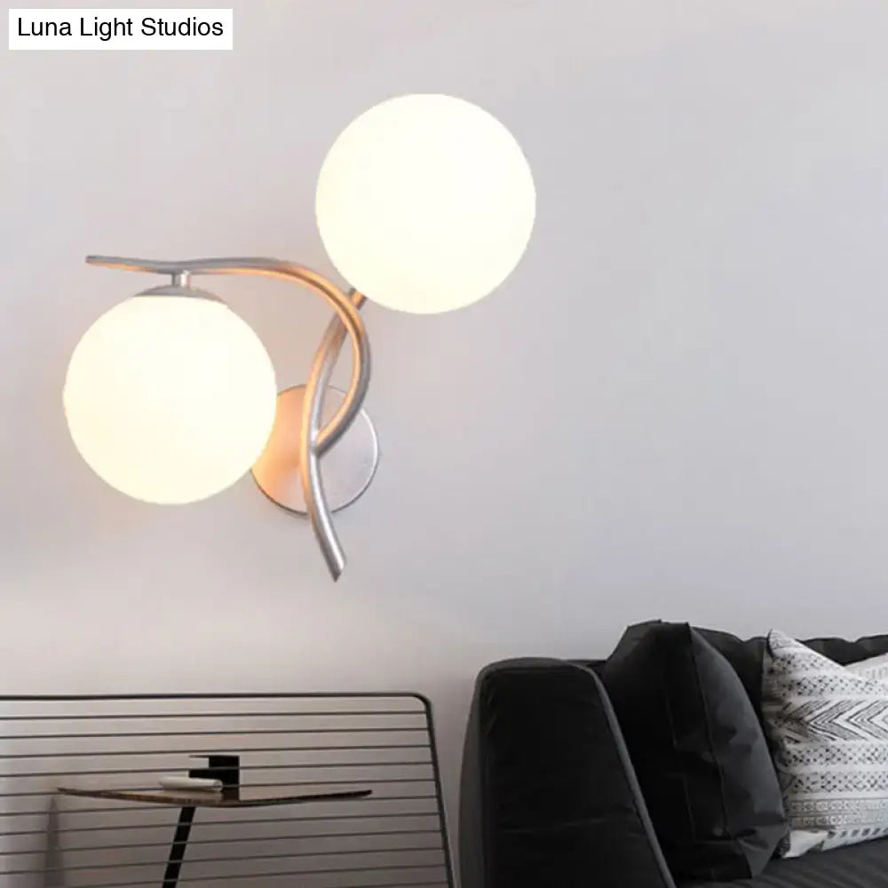 Modern two-light silver black wall sconce with curved metallic arms and milky glass globe shades for bedroom use