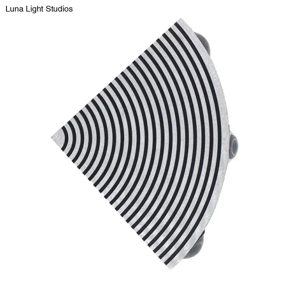 A sleek semi-circular black and silver wall lamp with concentric stripes for modernist living room lighting