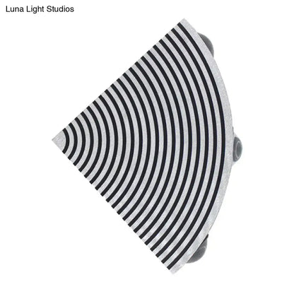 A sleek semi-circular black and silver wall lamp with concentric stripes for modernist living room lighting