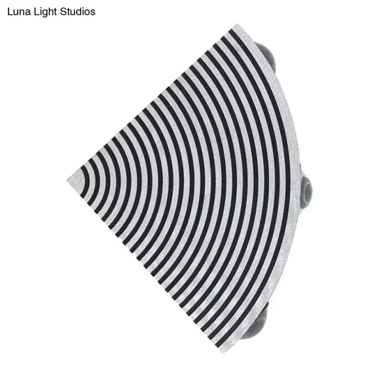 A sleek semi-circular black and silver wall lamp with concentric stripes for modernist living room lighting