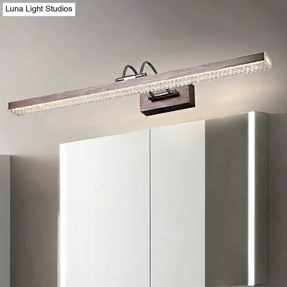 Modernist wall light with wood-grain finish and crystal led details mounted above white bedroom vanity cabinets