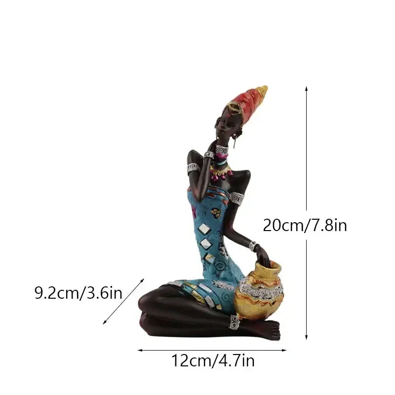A decorative resin figurine of an african black woman in a blue patterned dress with a red and yellow headdress for decorbites black women decor