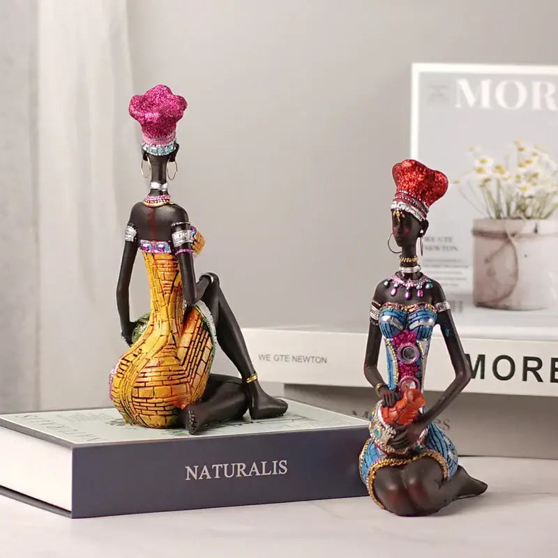 Two ornate dark-skinned black women resin art figures with glittery pink and red headdresses for decorbites black women decor