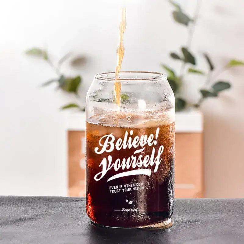 Clear glass shape beer glass cup engraved with white believe yourself text filled with dark soda for dining room use