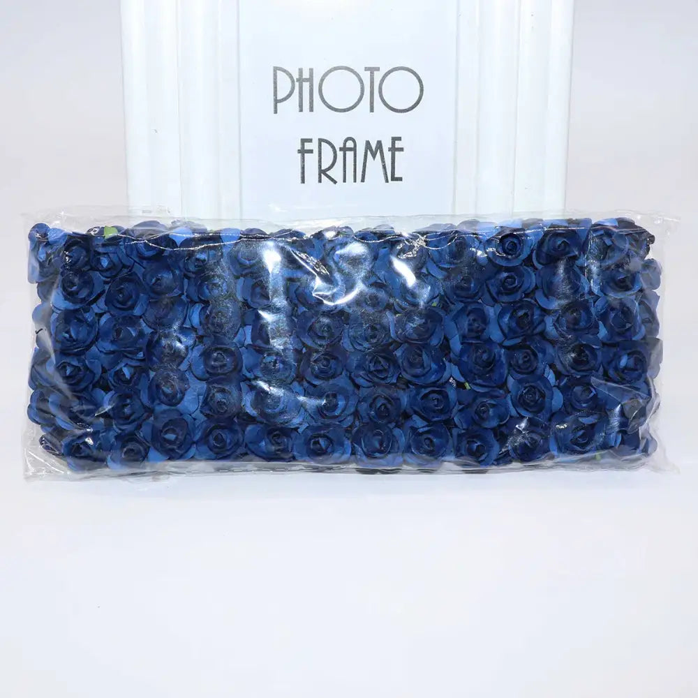 A package of navy blue decorbites 144pcs 2cm artificial paper roses neatly arranged and sealed in clear plastic packaging