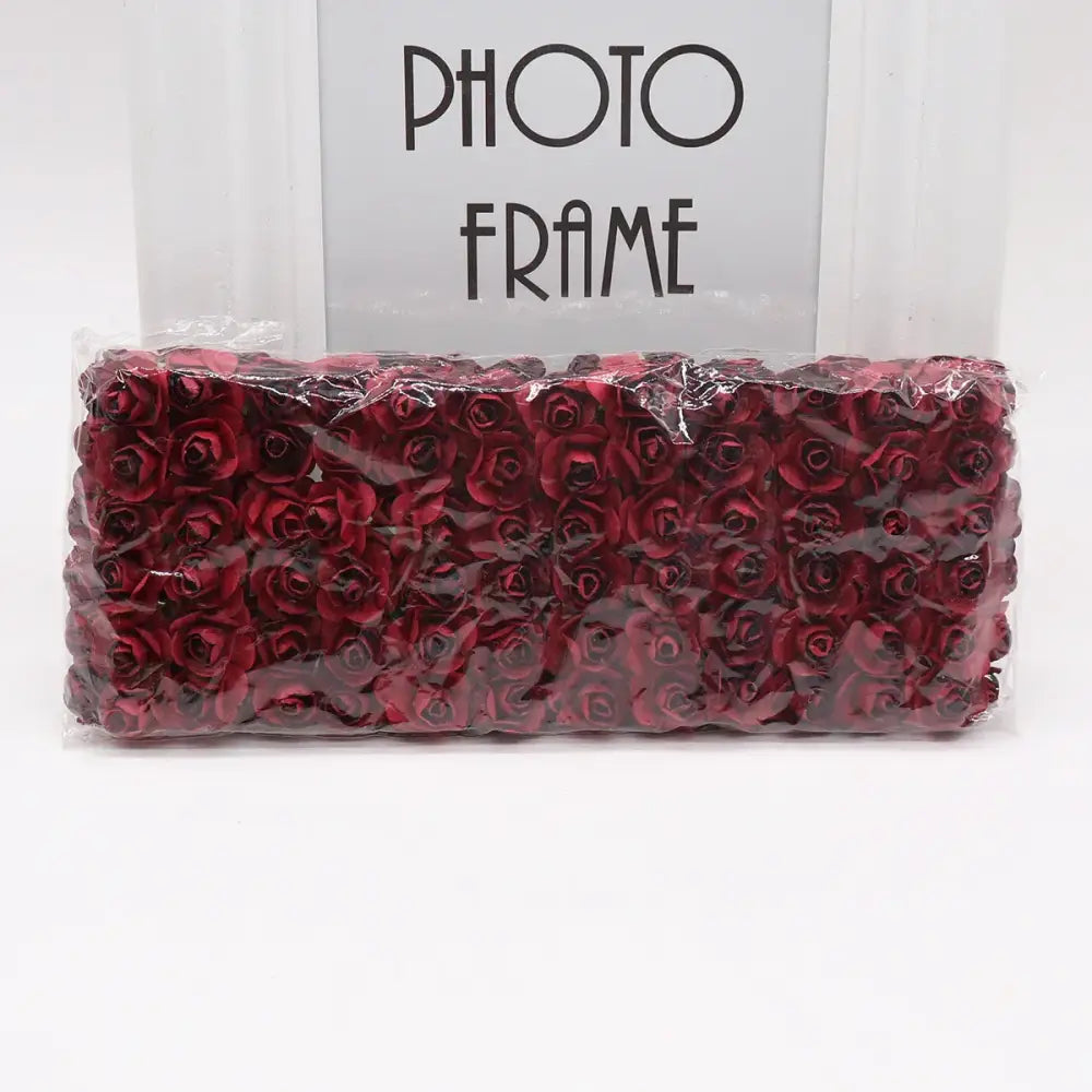 A package of deep red decorbites 144pcs 2cm artificial paper roses in clear plastic wrap for wedding decor