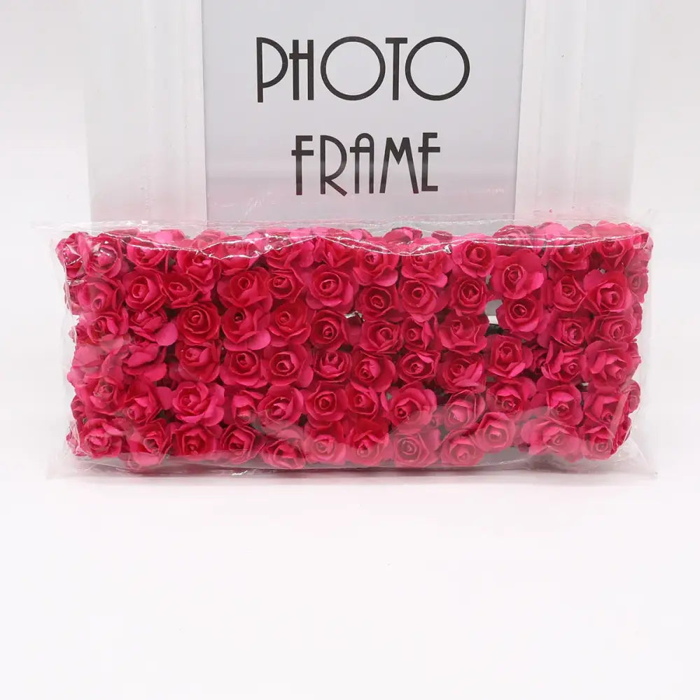 A package of decorbites 144pcs 2cm vibrant red 2cm artificial paper roses neatly arranged and sealed in clear plastic