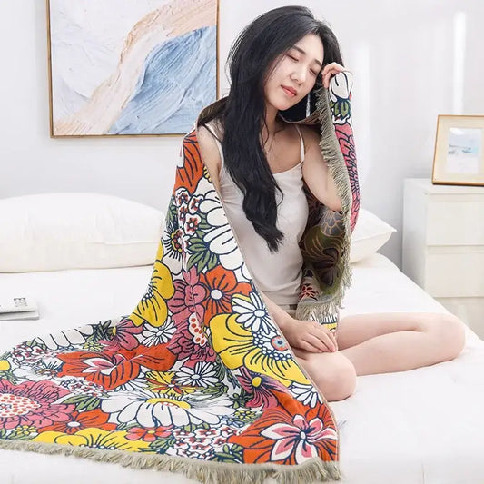A vibrant multicolor decorbites gauze flower bath towel with fringe trim used as a bedroom floral throw blanket
